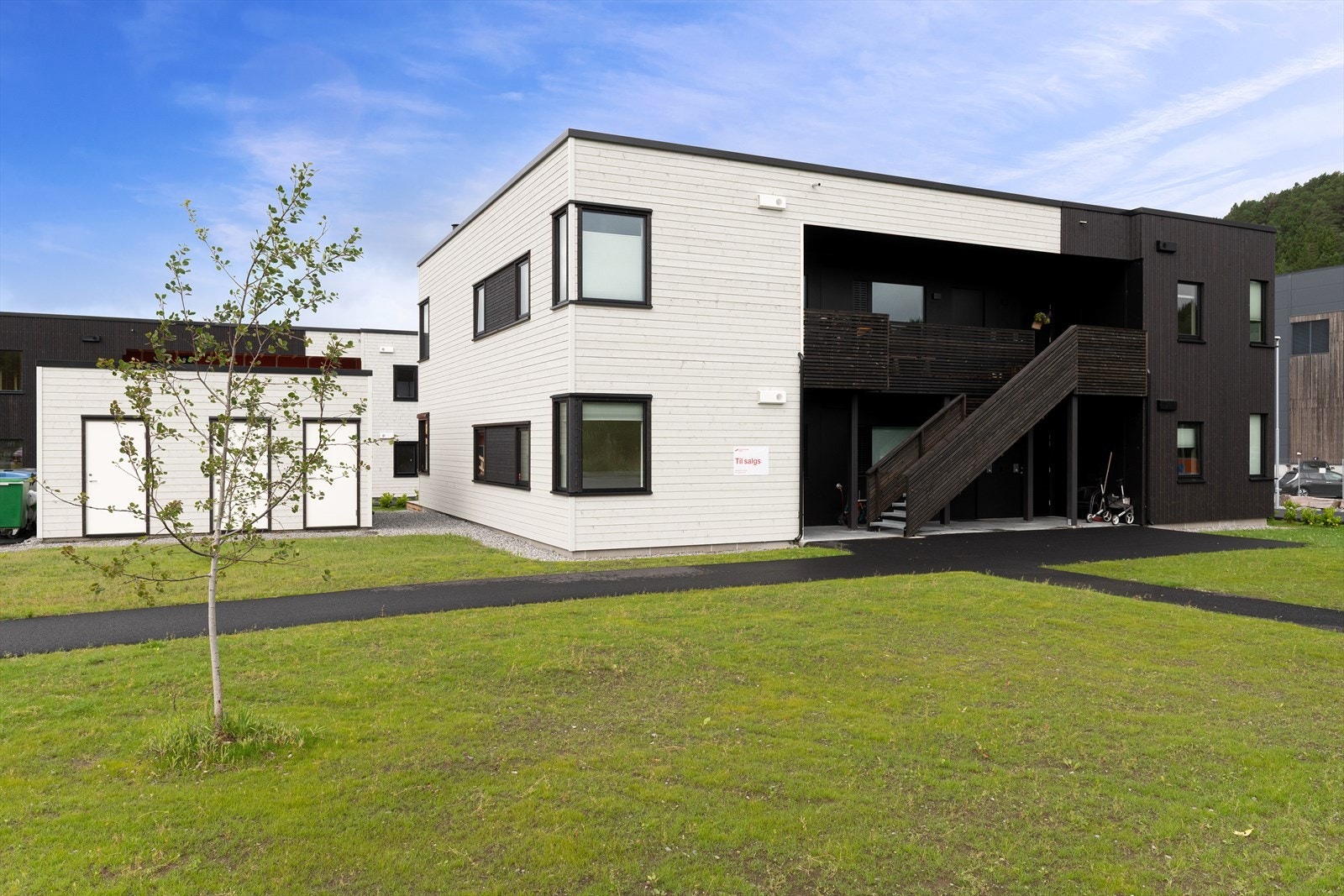 Sameiets tomt er pent opparbeidet med asfalterte adkomstveger og plen m/beplanting. Galleribilde