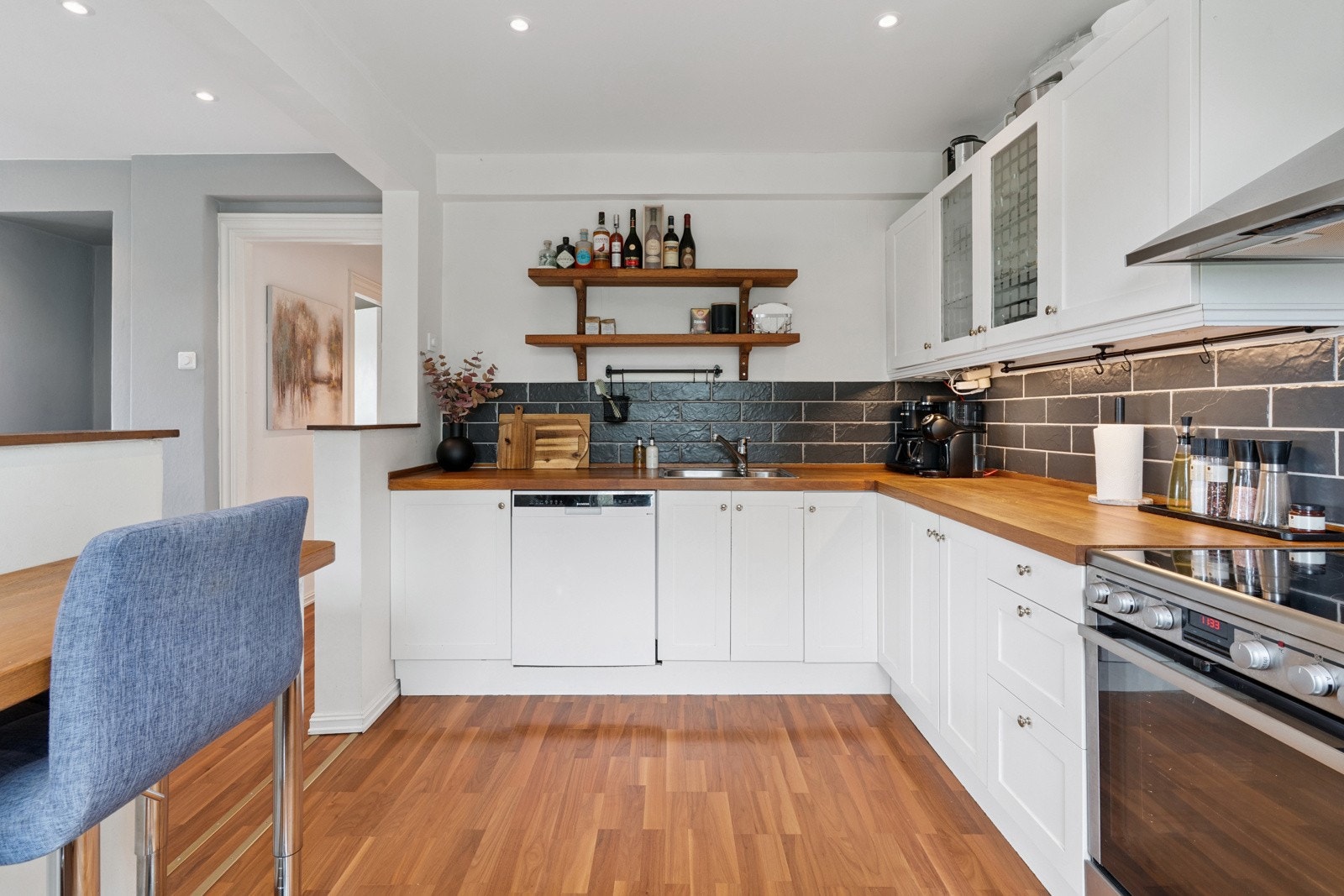 Profilert kjøkkeninnredning, eik heltre benkeplate, fliser over benk, kullfilter vifte og nedfelt kum. Galleribilde