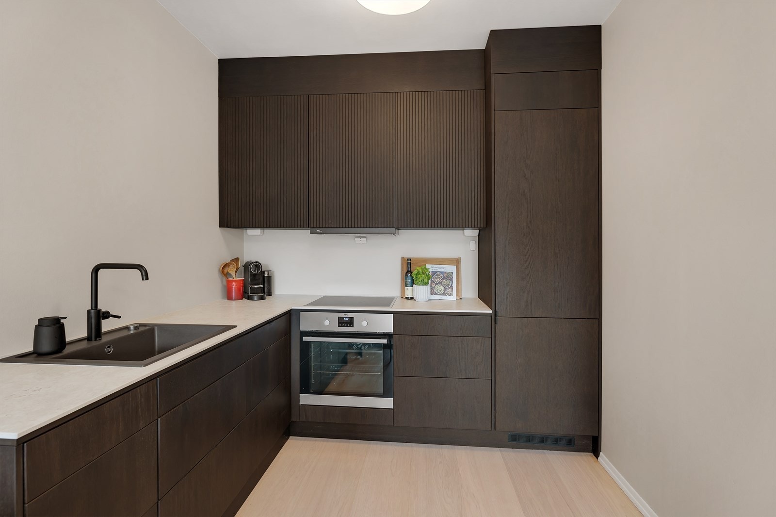 Integrerte hvitevarer i form av kjøl/fryseskap, oppvaskmaskin, stekeovn og induksjonsplatetopp. Galleribilde