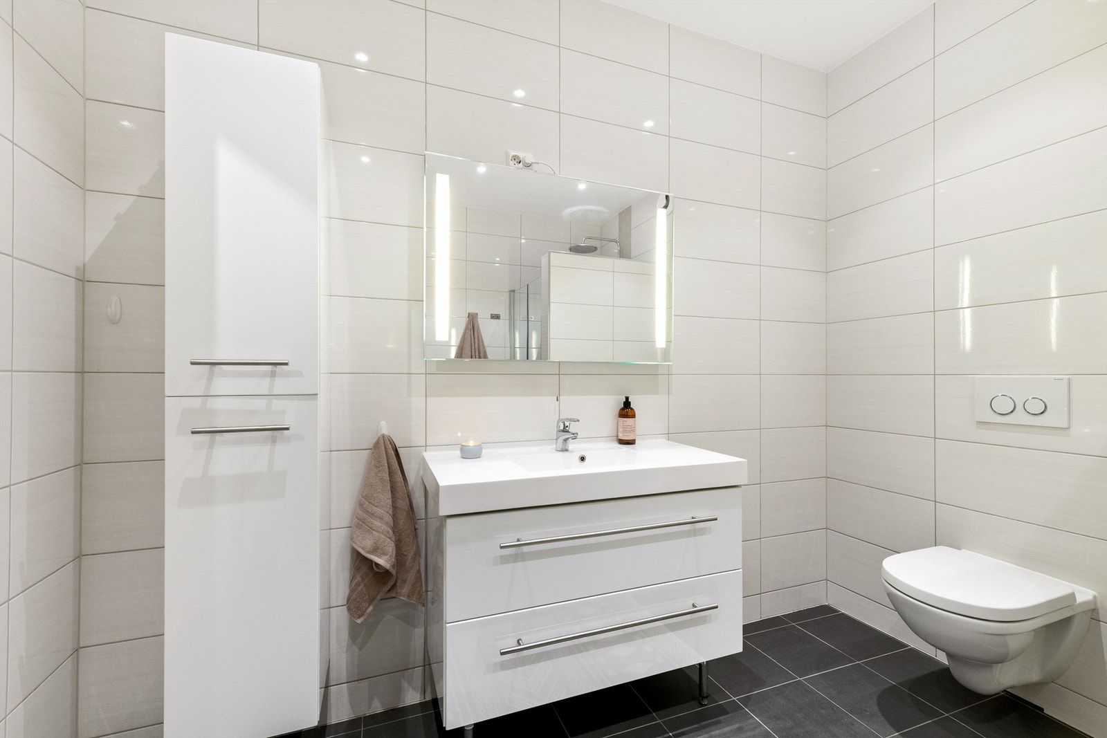 Badet ble oppgradert i 2013/2014. Hvit baderomsinnredning med skuffer og ovenpåliggende servant med ett-greps armatur. Speil med sidelys og stikkontakt over servant. I tillegg vegghengt baderomsmøbel. Vegghengt toalett Galleribilde