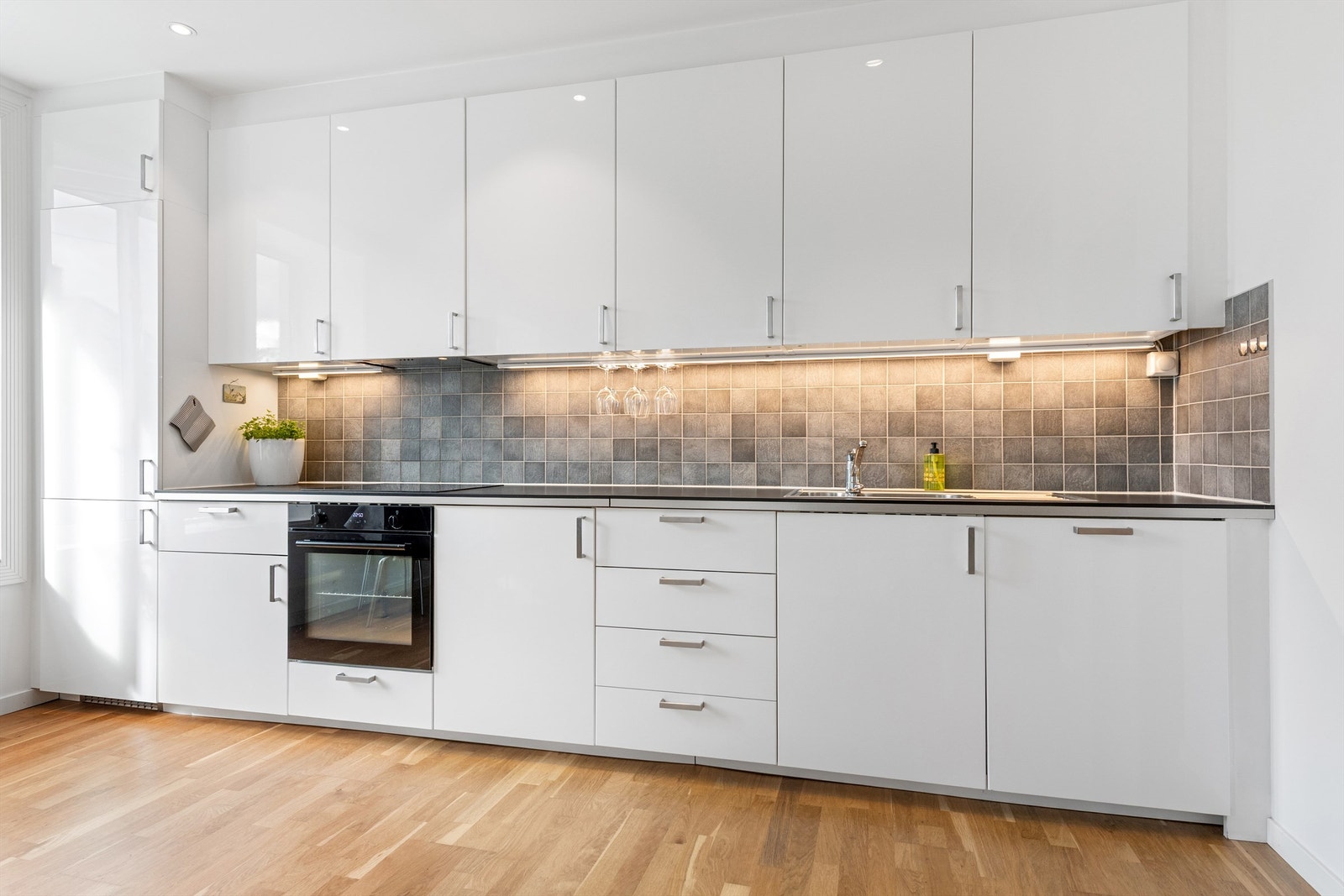 Ikea kjøkkeninnredning fra 2013/14 og med benkeplate av laminat med nedfelt oppvaskkum med ett-greps kjøkkenarmatur. Kjøkkenet har integrert stekeovn, platetopp, oppvaskmaskin og kjøelskap med fryser. Ventilator i overskap med komfyrvakt. Galleribilde