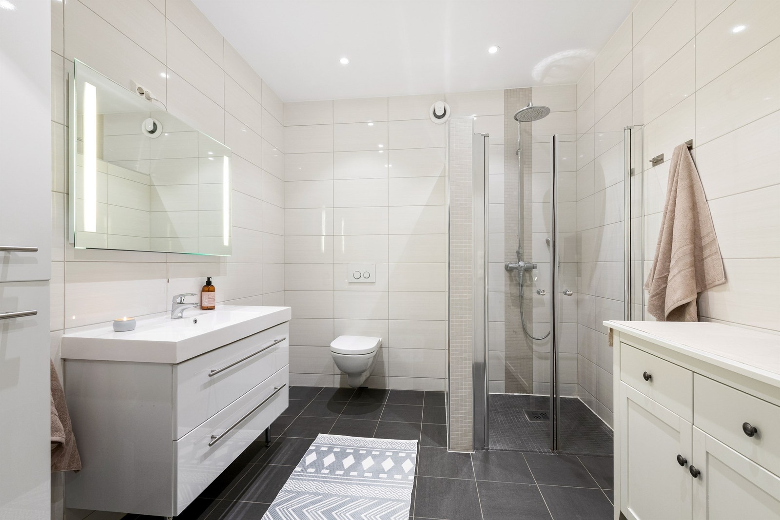 Badet har dusjnisje med glassvegger og vegghengt dusjarmatur med hånddusj og regndusj. Vegghengt toalett. Mekanisk avtrekksvifte i vegg. Galleribilde