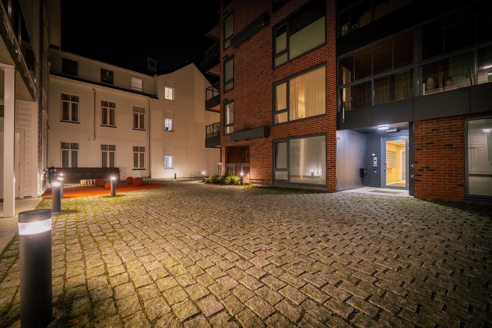 Byggets hovedinngang er skjermet fra veien og har et fint areal belagt med brostein og belysning Galleribilde