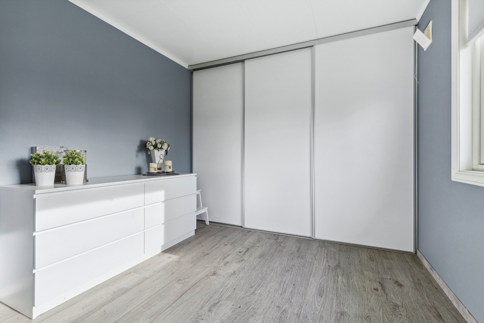 Det er bygget inn en stilren skyvedørsgarderobe i vegg. Galleribilde