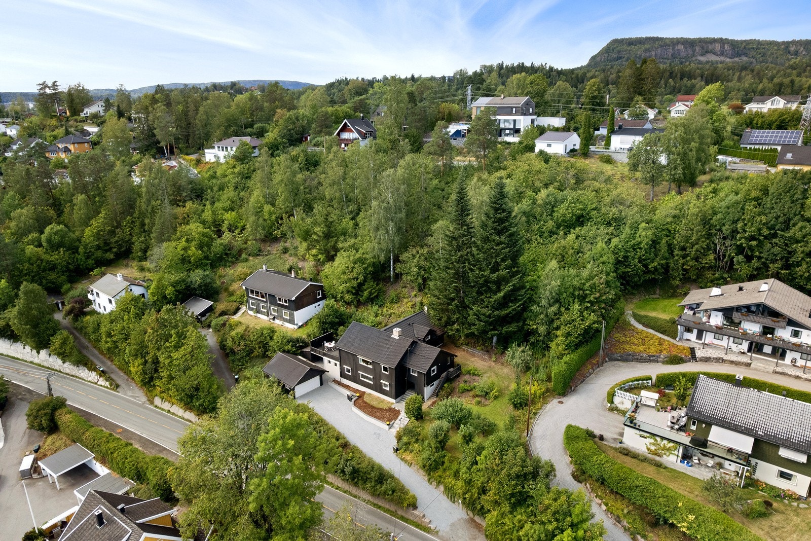 Høydefoto av eiendommen. Tomten fremstår som naturtomt på oversiden av huset Galleribilde