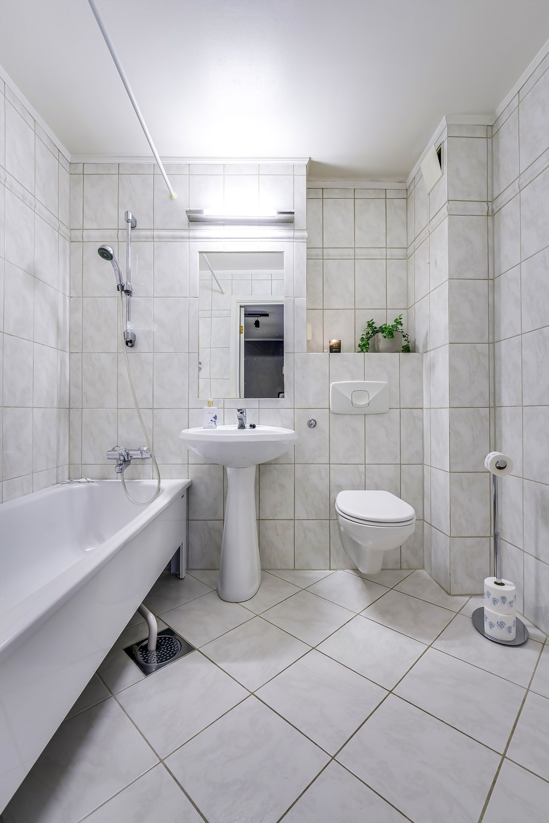 Badet er innredet med servant, vegghengt toalett og badekar. Galleribilde