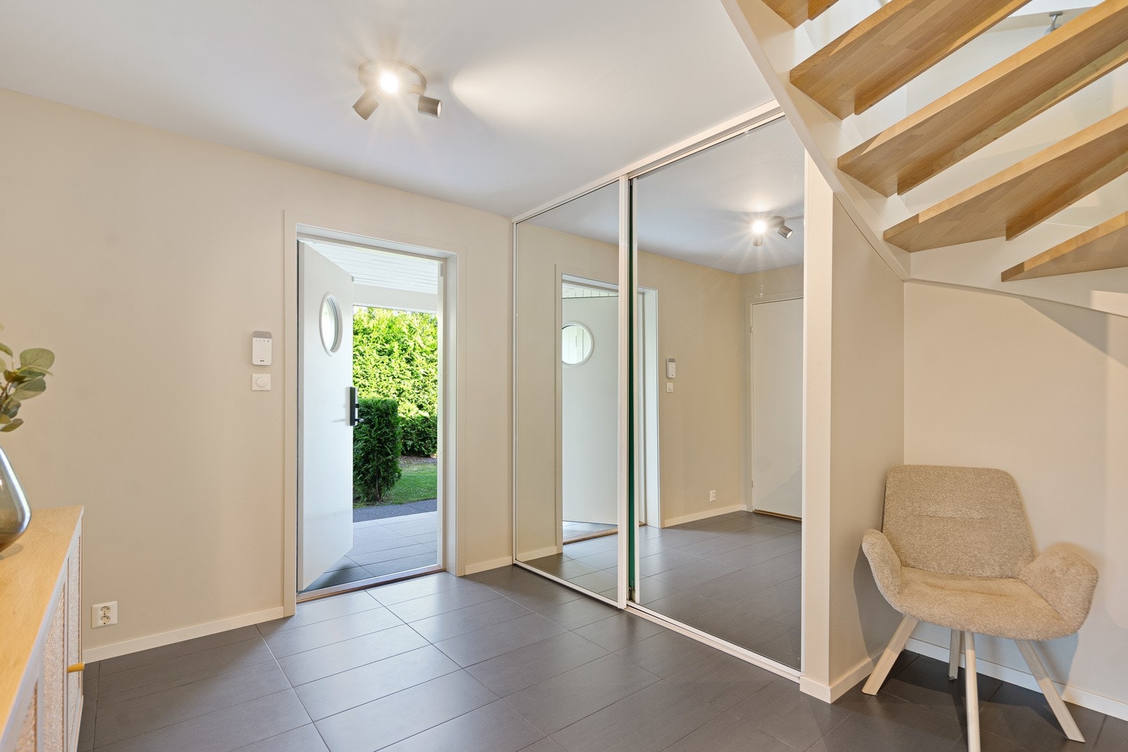 Du møtes av en stor hall med fliser og varmekabler, skyvedørsgarderobe med helspeil Galleribilde