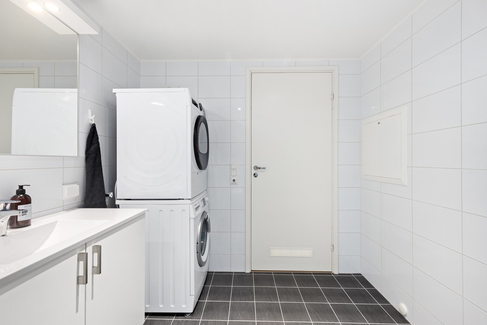 Vegghengt toalett med innbygd sisterne. Opplegg for vaskemaskin. Fliser på gulv og vegger. Varmekabler i gulv og downlights i nedsenket himling Galleribilde