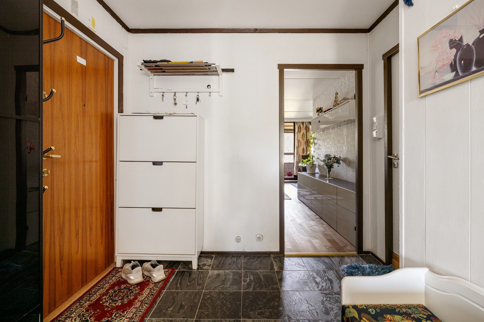 Entréen har mørke fliser på gulv og lysmalte overflater. Galleribilde