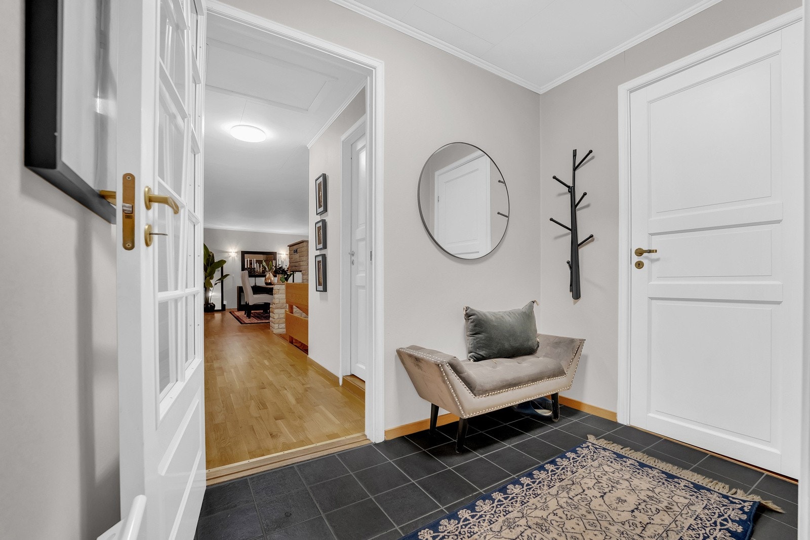 Lyst inngansparti med praktisk skyvedørsgarderobe, og inngang til gjestetoalett Galleribilde