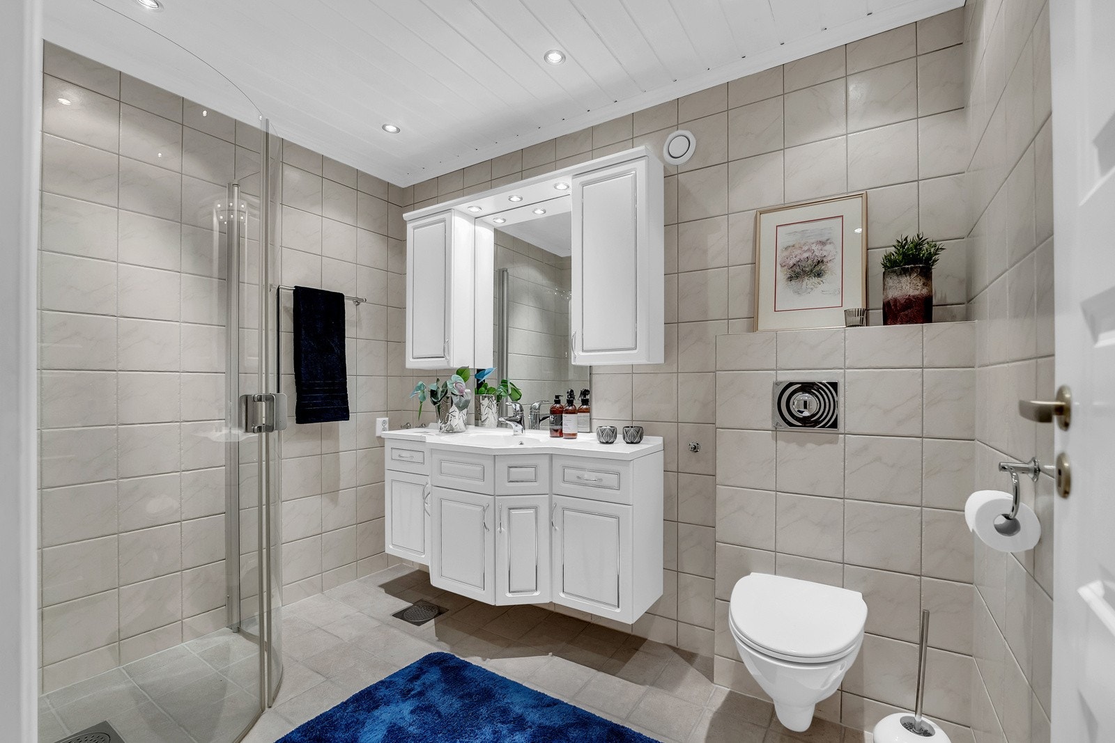 Lyst og pent bad med varme i gulv. På badet er det baderomsinnedning med servant, speil med belysning, vegghengt toalett og dusjhjørne med glassvegger Galleribilde