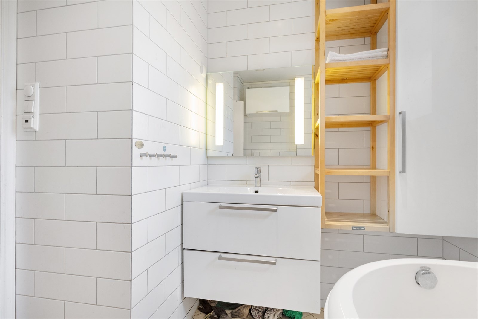 Badet har flis på gulv og flis på vegger. Downlights og malt overflate i himling. Gulvvarme. Utstyrt med naturlig avtrekk, badekar, veggmontert wc og servantskap med ett greps blandebatteri fra Oras. Galleribilde