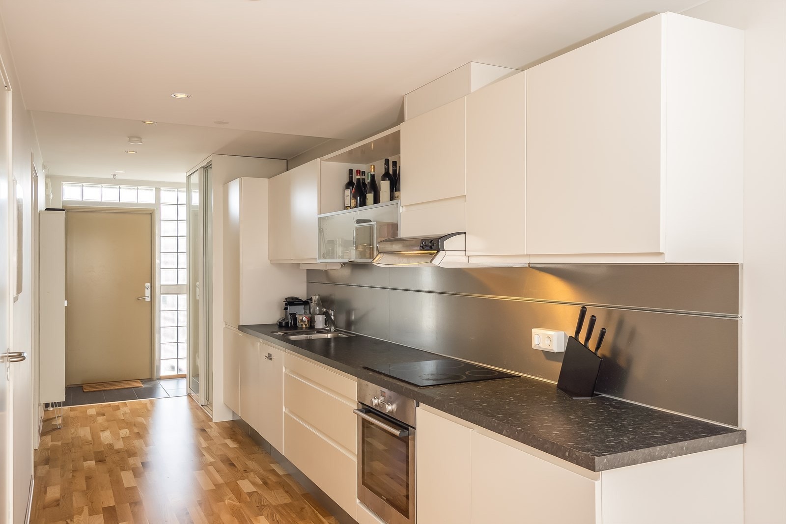 Stilrent kjøkken fra byggeår med glatte fronter og integrerte hvitevarer som kjøleskap, stekeovn, platetopp og oppvaskmaskin. Galleribilde