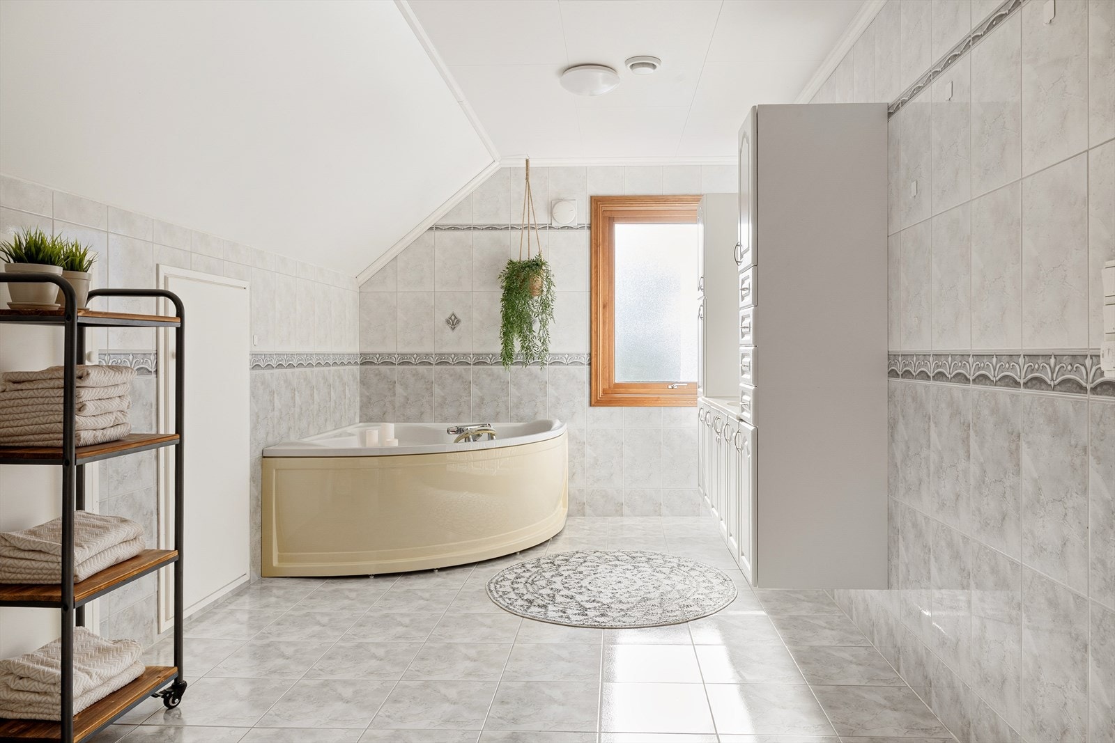 Det er helfliset i lyse, nøytrale farger, og innredet med vegghengt toalett, servant med underskap og dusjkabinet og badekar. Galleribilde