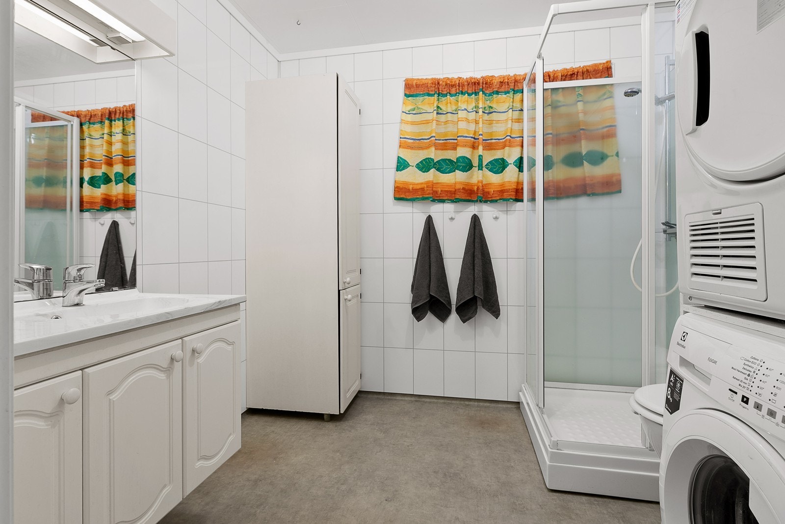 Badet innehar dusjhjørne, servant med underskap, wc og opplegg for vaskemaskin. Galleribilde