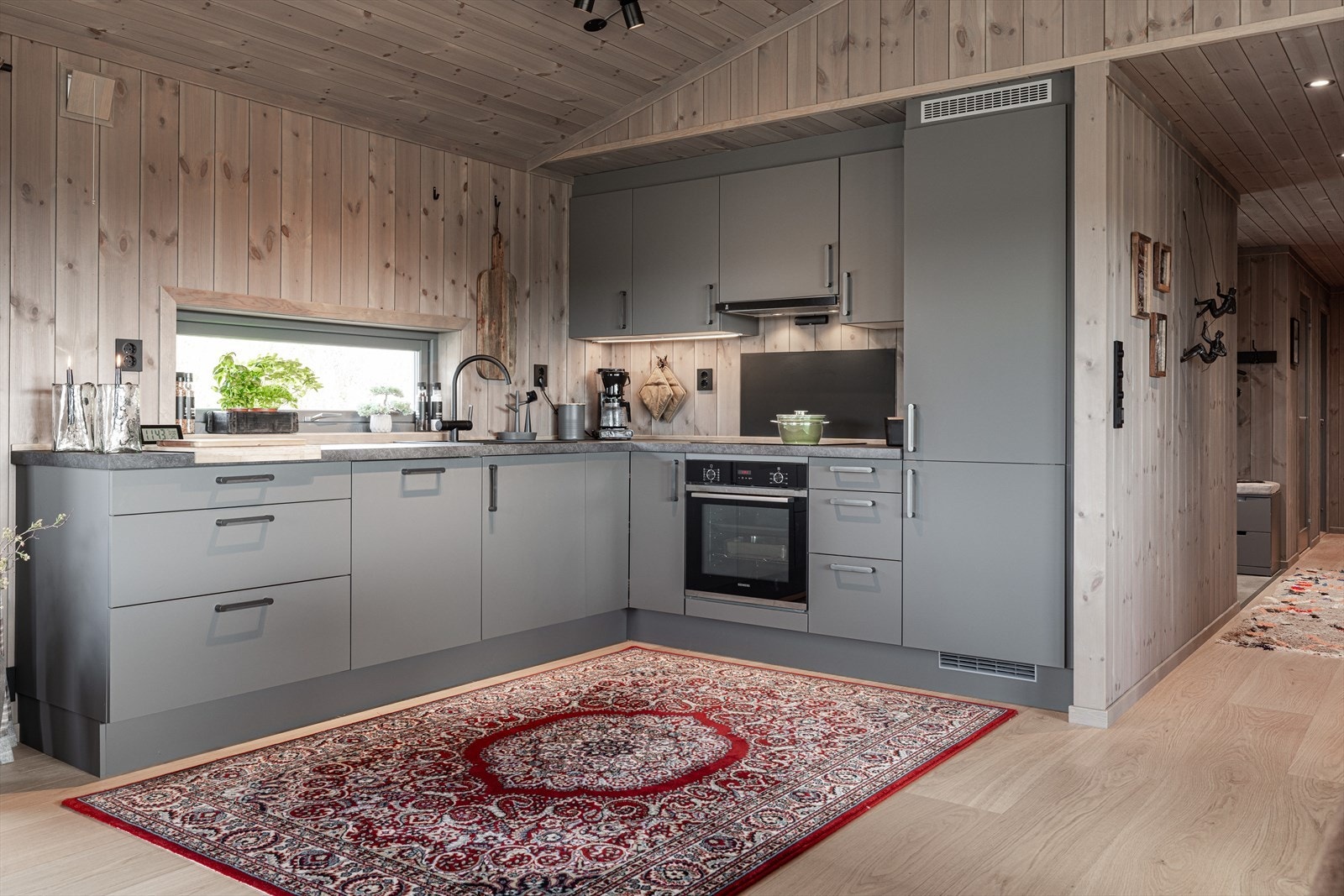 Kjøkken inneholder behandlet innredning med glatte fronter. Integrerte hvitevarer som komfyrtopp, stekovn, oppvaskmaskin, kjøl Galleribilde