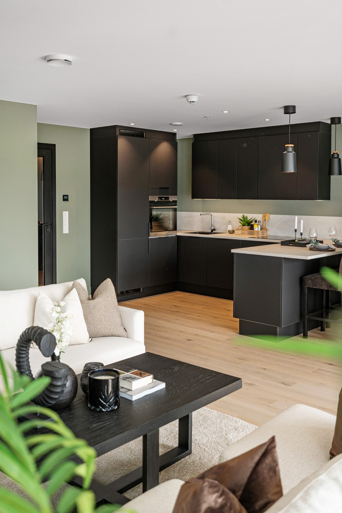 Stilrent kjøkken med mørke fronter og lyse benkeplater. Galleribilde