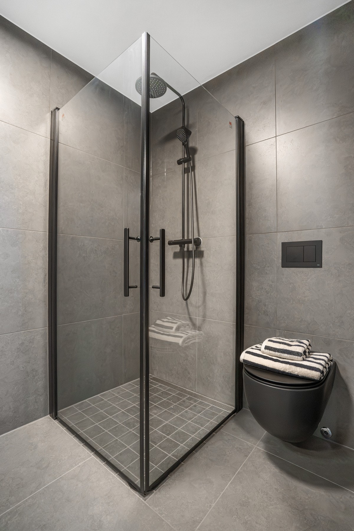 Romslig dusj med glassvegger og sorte detaljer. Galleribilde