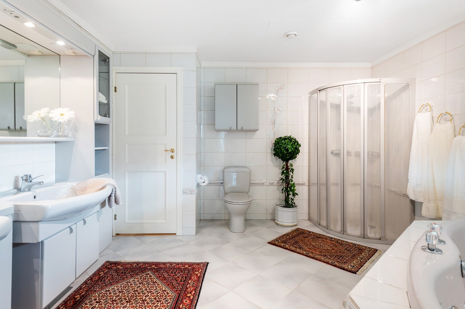 Stort bad med dobbelvask, godt med over og underskap, toalett, boblebad samt dusjhjørne. Galleribilde