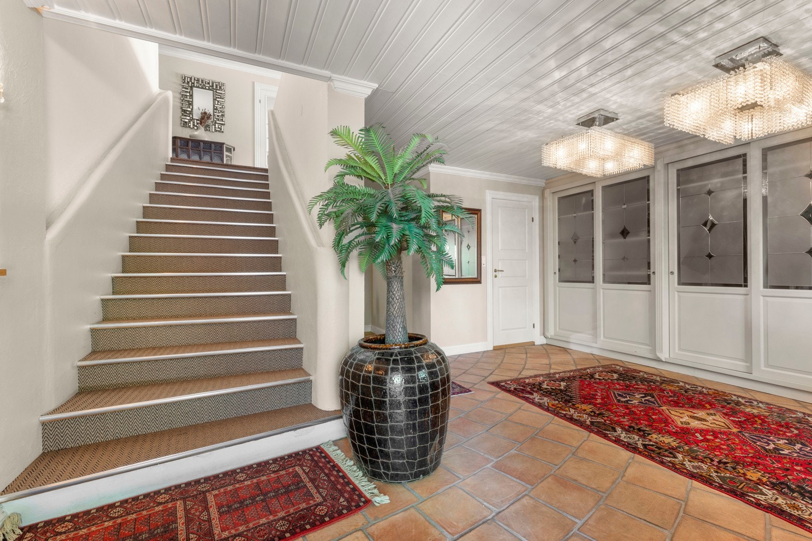 Velkommen inn til en romslig entré med trappeoppgang til hovedetasjen.