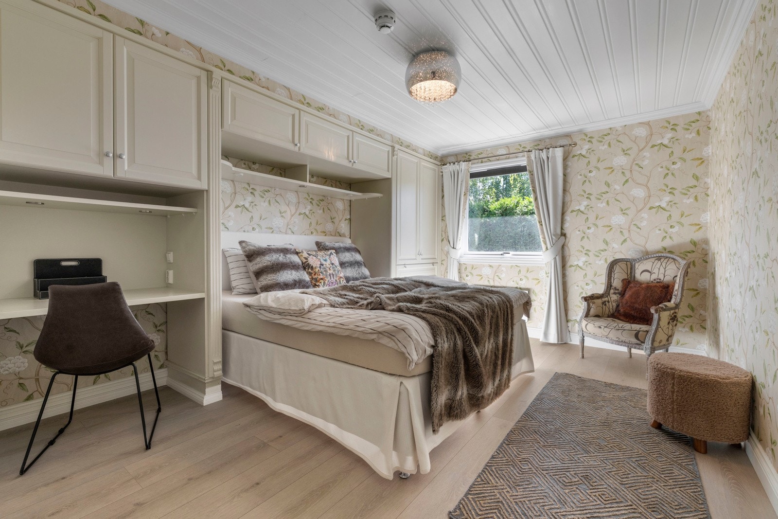 Med tapetet som går igjen på veggene skapes en rød tråd i interiøret. Dobbeltsengen er innrammet av skapplass - en smart utnyttelse av rommet.