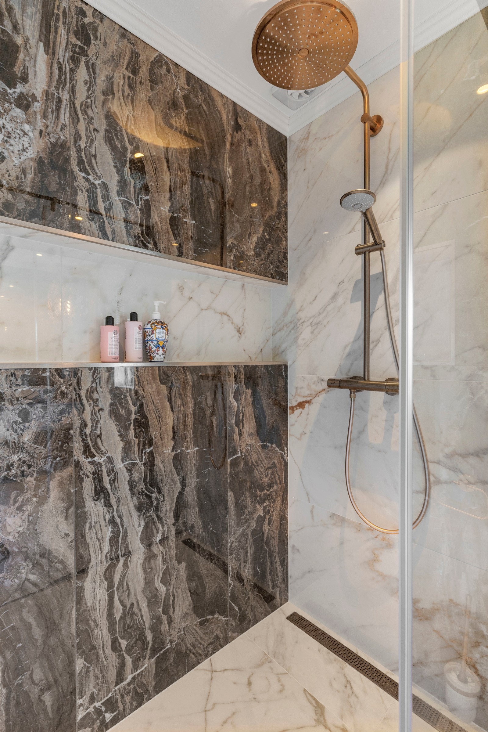 Den romslige dusjsonen har en stilren glassvegg i herdet glass og en praktisk innebygd hylle til såper og produkter. Dusjen byr på både  waterfall -funksjon og håndholdt dusjhode.