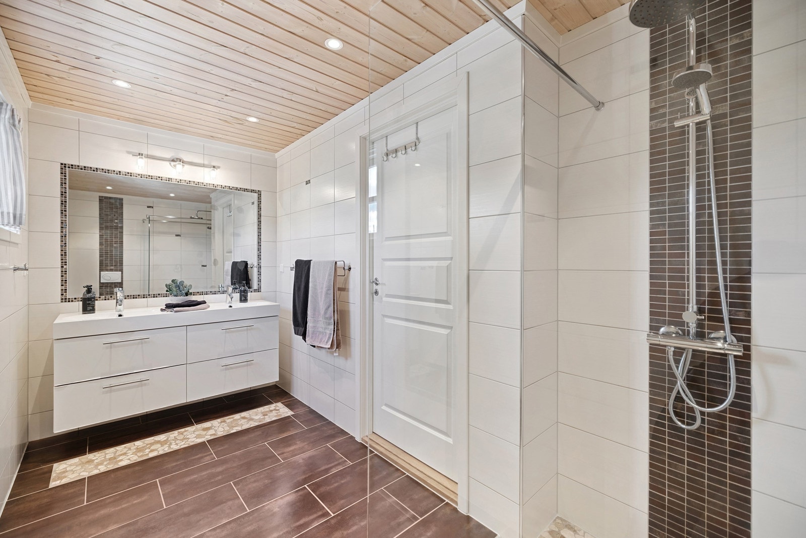 Badet er utstyrt med et romslig dusjhjørne og vegghengt toalett Galleribilde