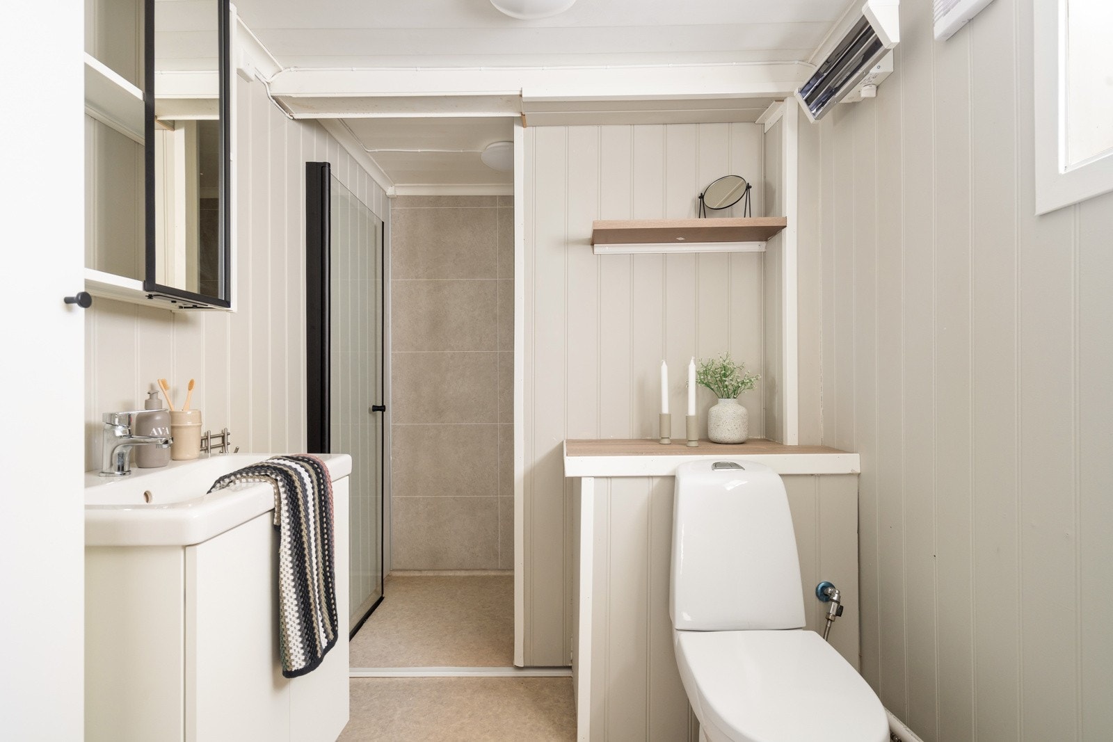 Boligen har et bad med dusjhjørne, servant og toalett. Galleribilde