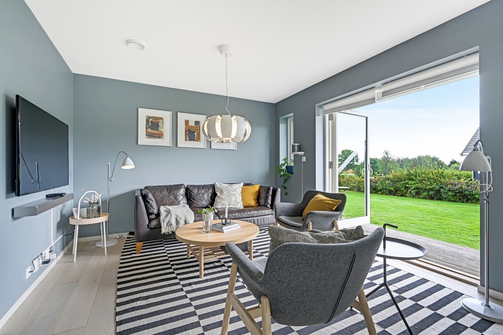 Man kan enkelt åpne dører ut til terrassen og hagen, slik at boligen og hagen går i ett - perfekt på varme sommerdager. Galleribilde