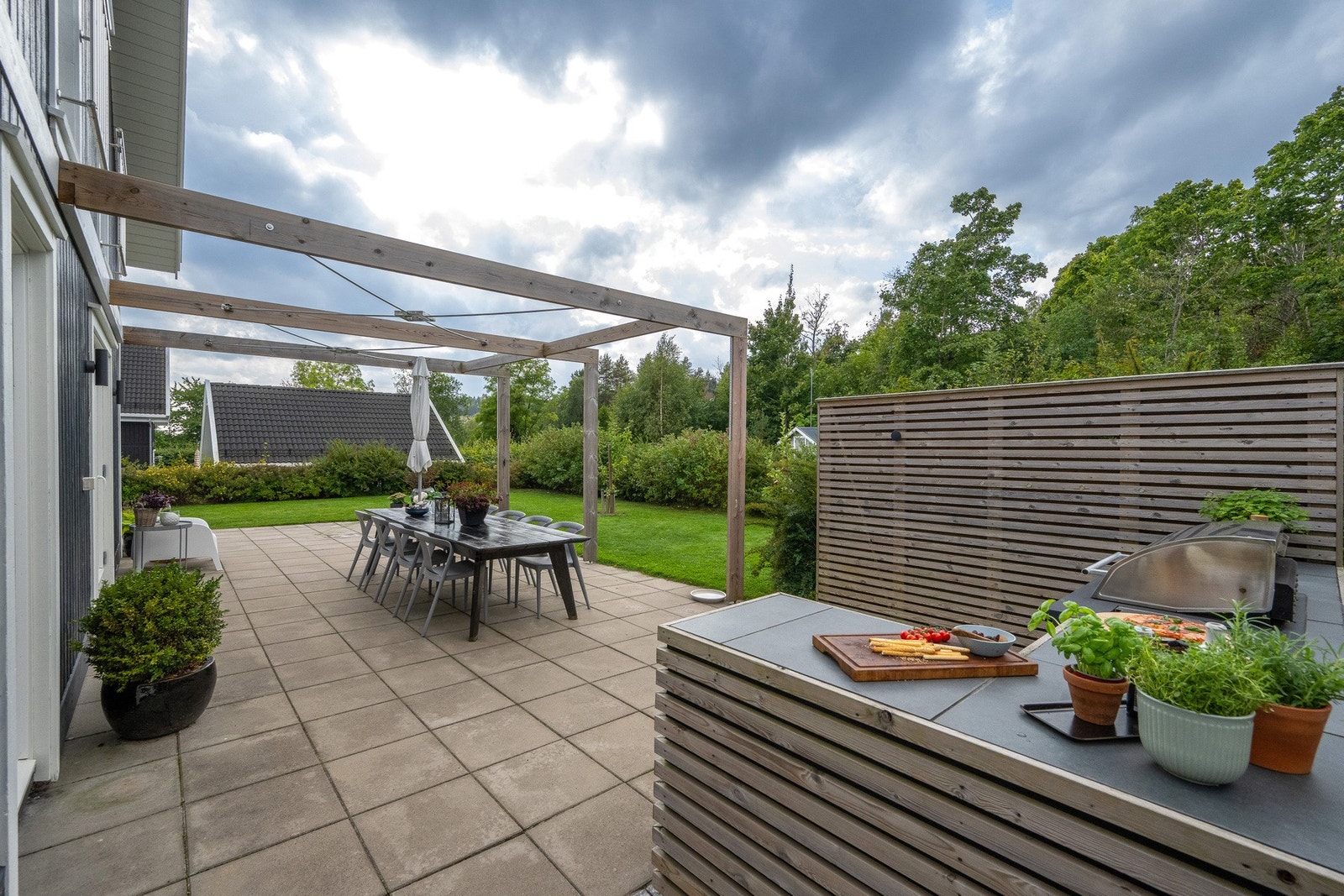 Hagen er pent opparbeidet med steinheller, pergola og et stilig utekjøkken som enhver vil sette pris på. Galleribilde