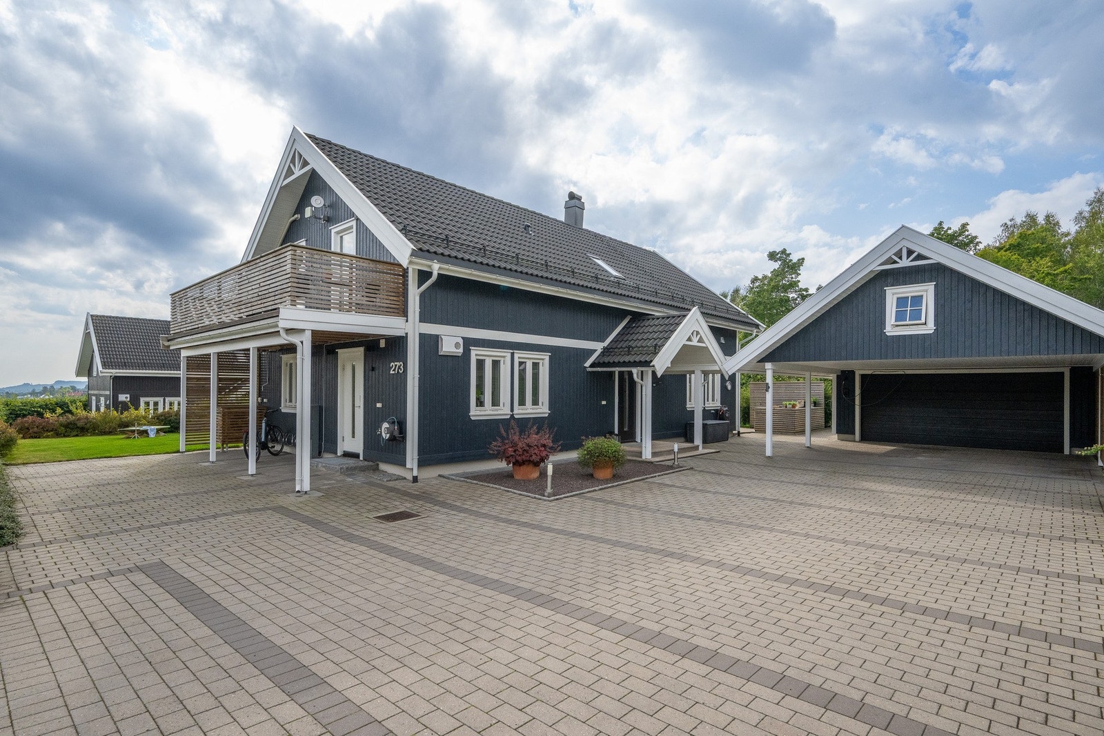 Tomten er svært pent opparbeidet med dekorativ belegningsstein. Hekken blomstrer i hvitt og gult på ulike tidspunkter og alt er laget med tanke på enkelt vedlikehold, slik at du kan nyte solen. Galleribilde