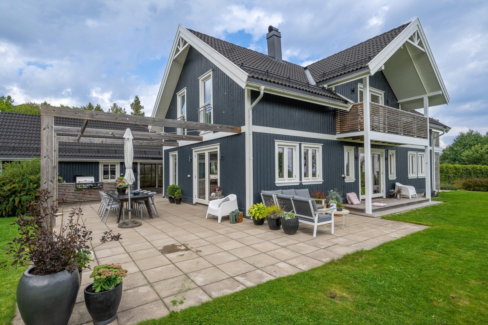 Uteområdet er pent opparbeidet med stor gressplen, samt steinheller, pergola og flere terrasser og balkonger. Her vil hele familien trives! Galleribilde