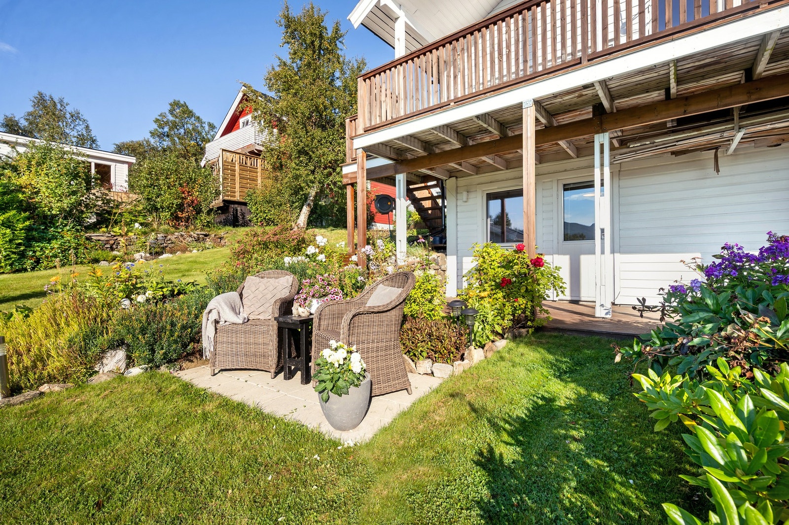 Flott opparbeidet hage med markterrasse og flere blomsterbed. Galleribilde