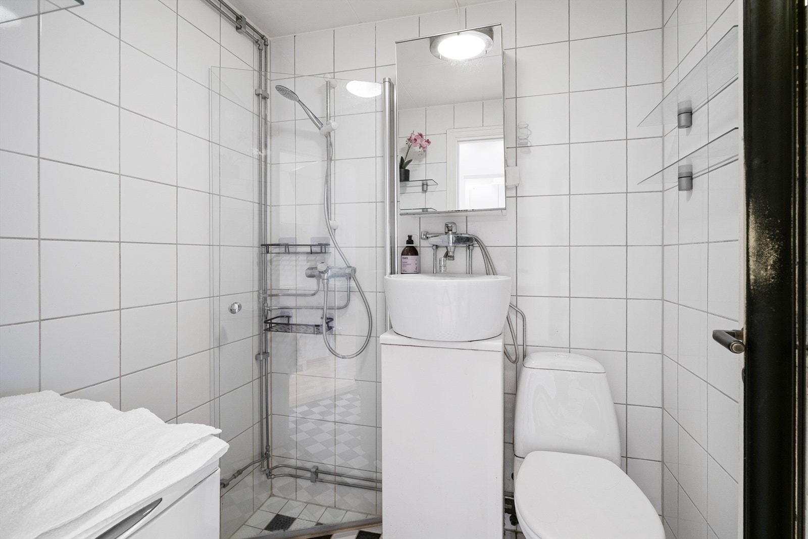 Badet er utstyrt med dusjhjørne, opplegg for vaskemaskin, servant, servantskap, wc og naturlig avtrekk Galleribilde
