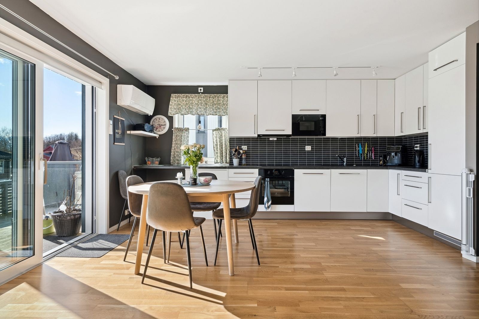 Moderne og luftig kjøkken-stue i åpen løsning, flommet med naturlig lys fra store vinduer. Galleribilde