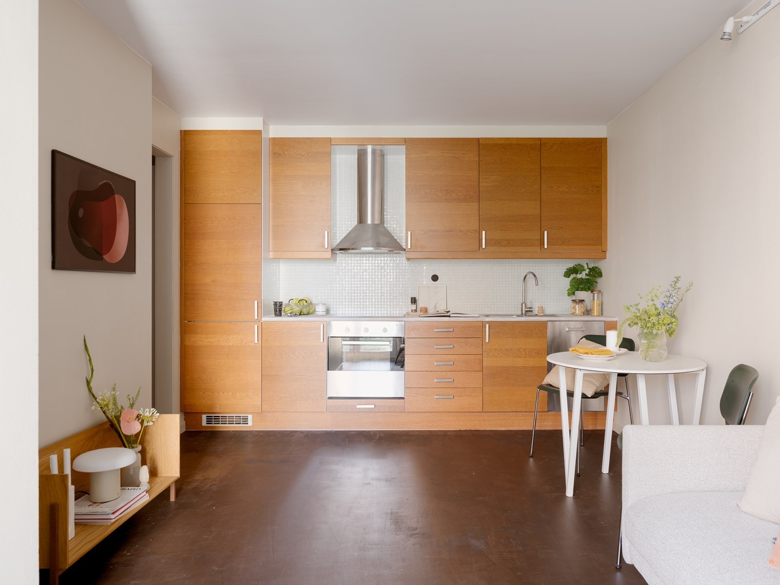 Stue og kjøkken ligger i en åpen løsning, som gjør boligen sosial og luftig. Kjøkkenet er integrert i vegg på en smakfull måte, og utgjør et stilrent møbel i seg selv. Galleribilde