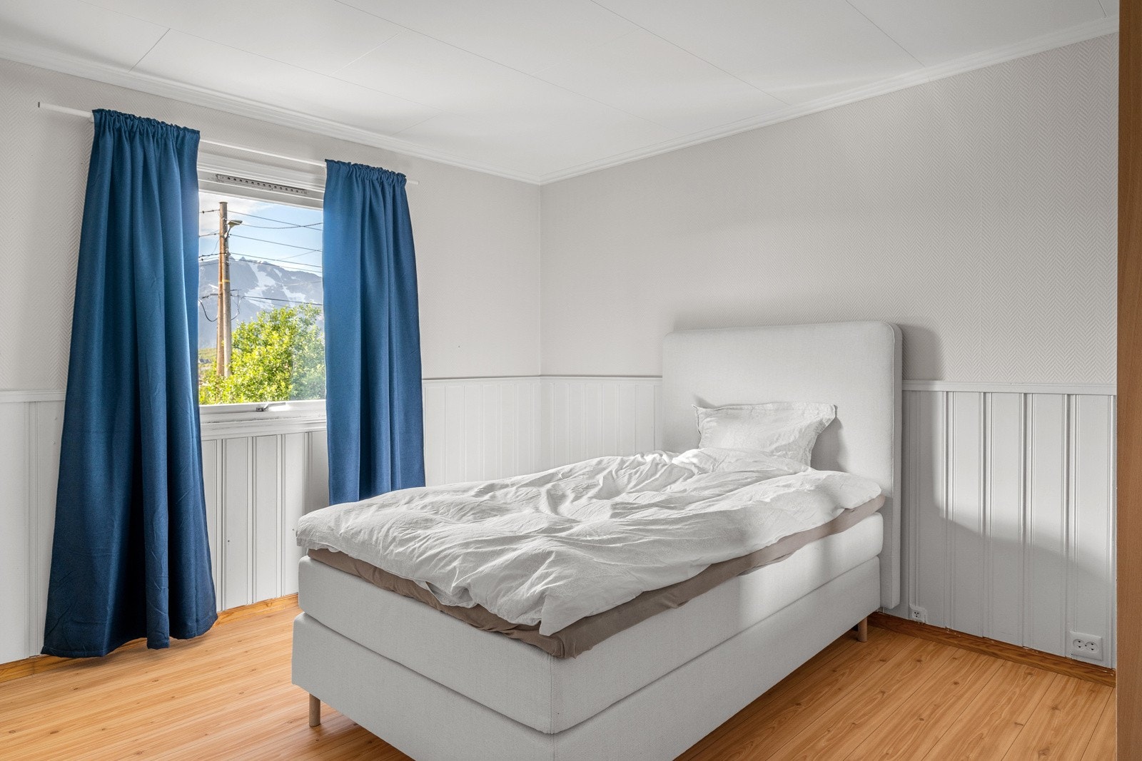 Soverom med god plass til stor seng og tilhørende nattbord.