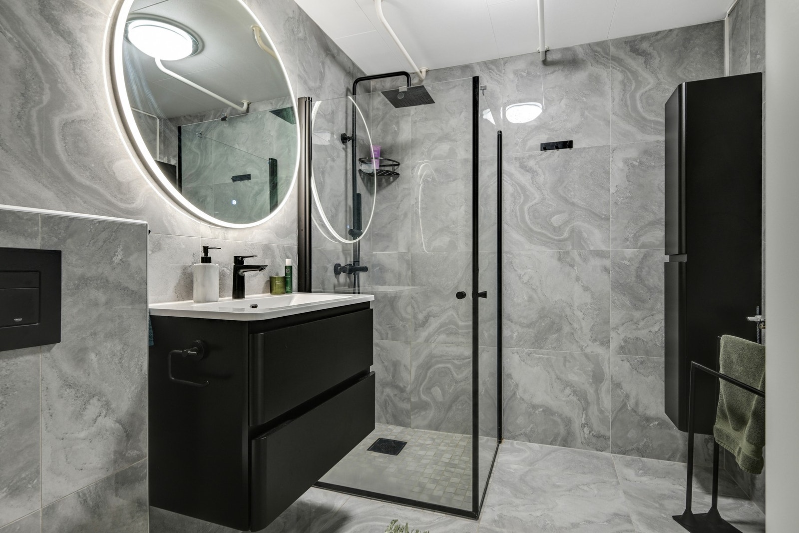 Boligen kan skilte med ett baderom i hver etasje, hvorav dette er kombinert vaskerom/bad med en mørk og moderne stil. Galleribilde