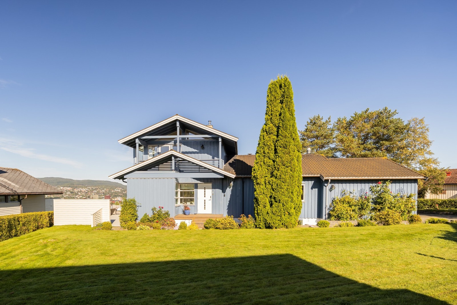 Tomten er pent opparbeidet med terrasse mot sør, hellebelagt uteområde mot vest samt flat plenareal mot øst.