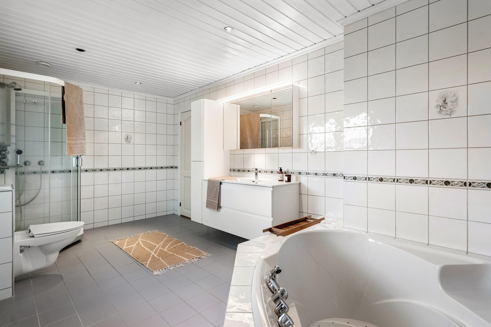 Her finner du vegghengt toalett, servant med underskuffer og tilhørende sideskap som gir godt med oppbevaringsplass. I tillegg er badet utstyrt med dusjkabinett, boblebadekar og opplegg for vaskemaskin Galleribilde