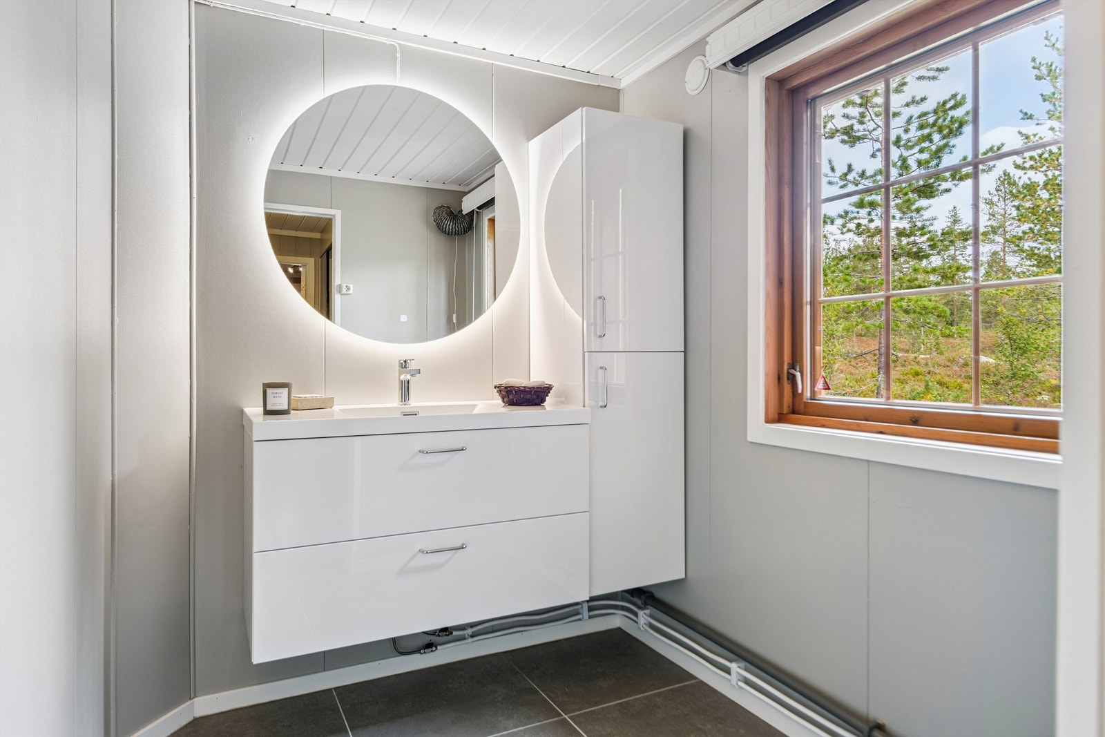 Innredningen består av en moderne servant med skuffer og et speil med integrert belysning. Galleribilde