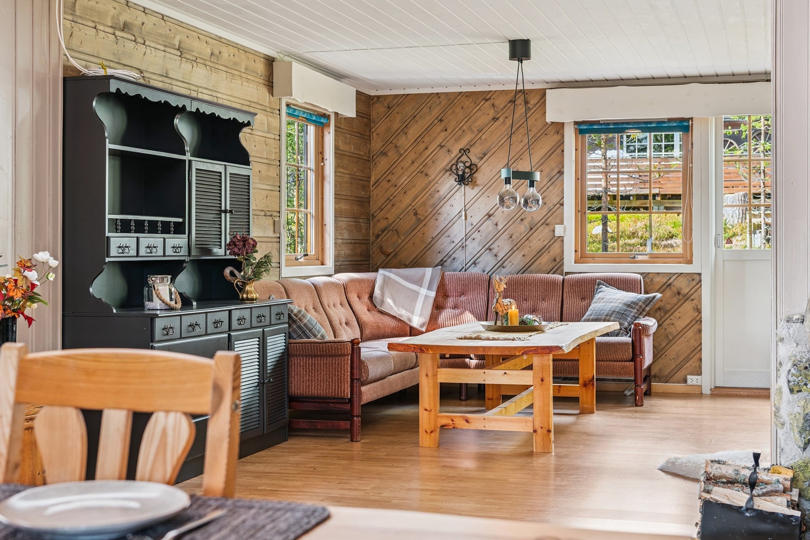 Vegger med trepanel og store vindusflater med sprosser gir en klassisk og lys hyttefølelse. Galleribilde