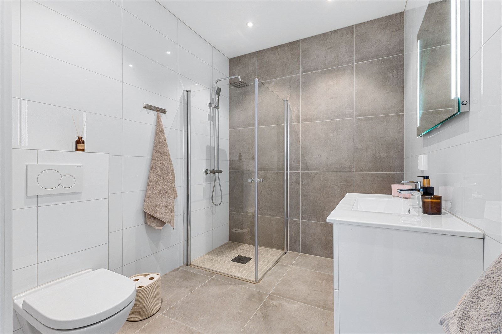 Badet er innredet med moderne servantmøbel, dusjnisje og toalett, og har flislagte overflater og varmekabler for ekstra komfort. Galleribilde