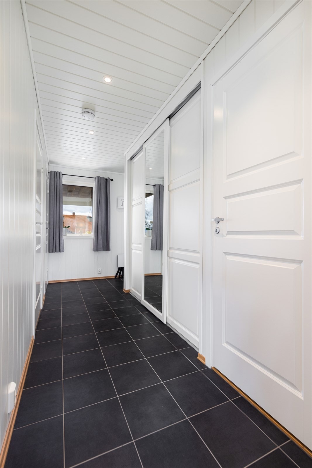 Entreen har fliser på gulv med gulvvarme og mdf på vegg. Det er spotter i tak. Galleribilde