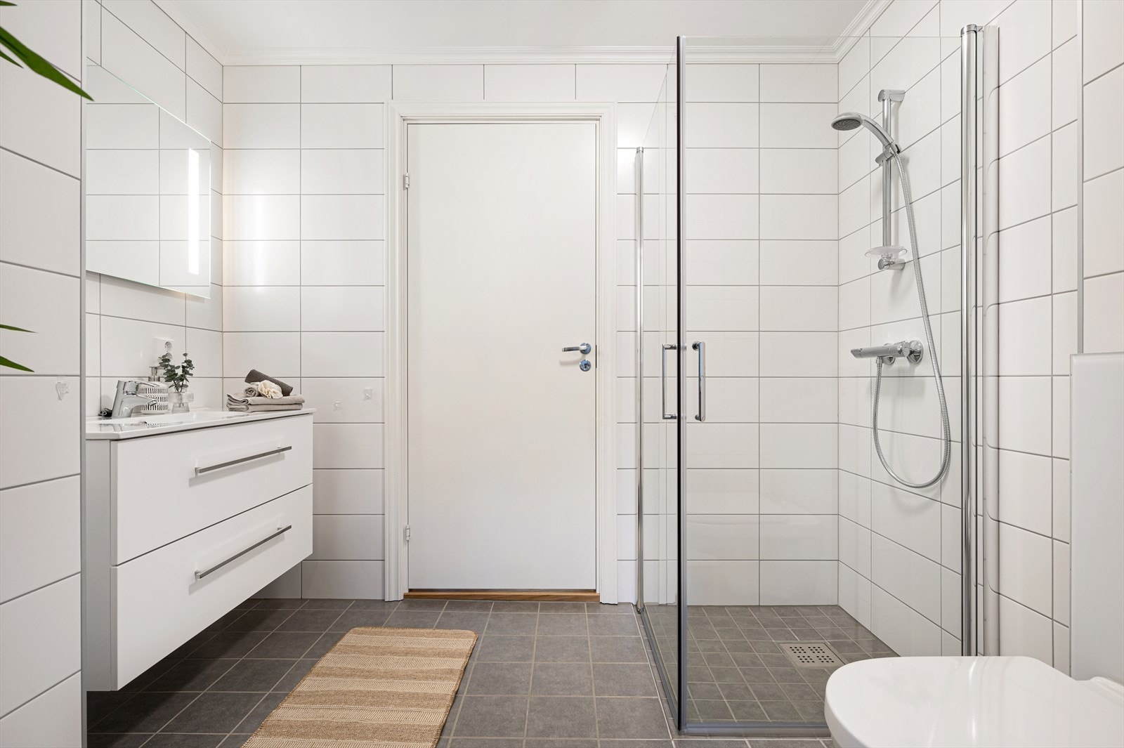 Badet er innredet med dusjhjørne, vegghengt toalett og servant Galleribilde