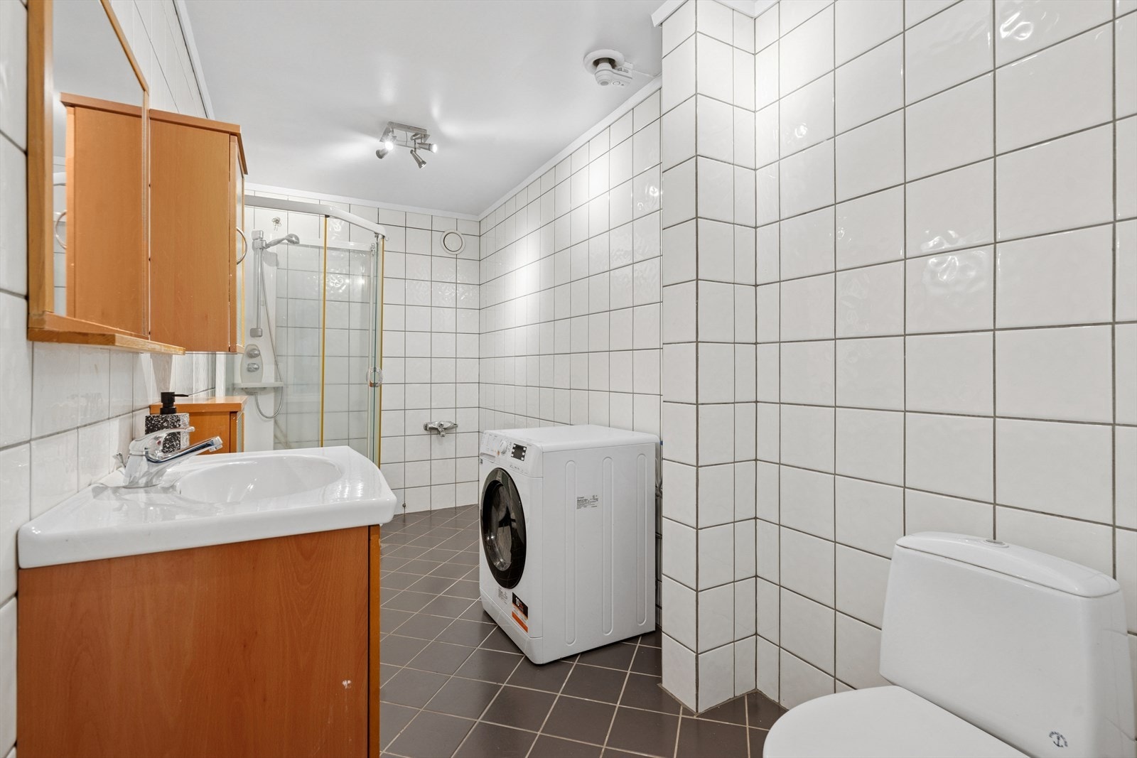 Baderommet er helflislagt og er innredet med servantskap, wc og dusjkabinett Galleribilde