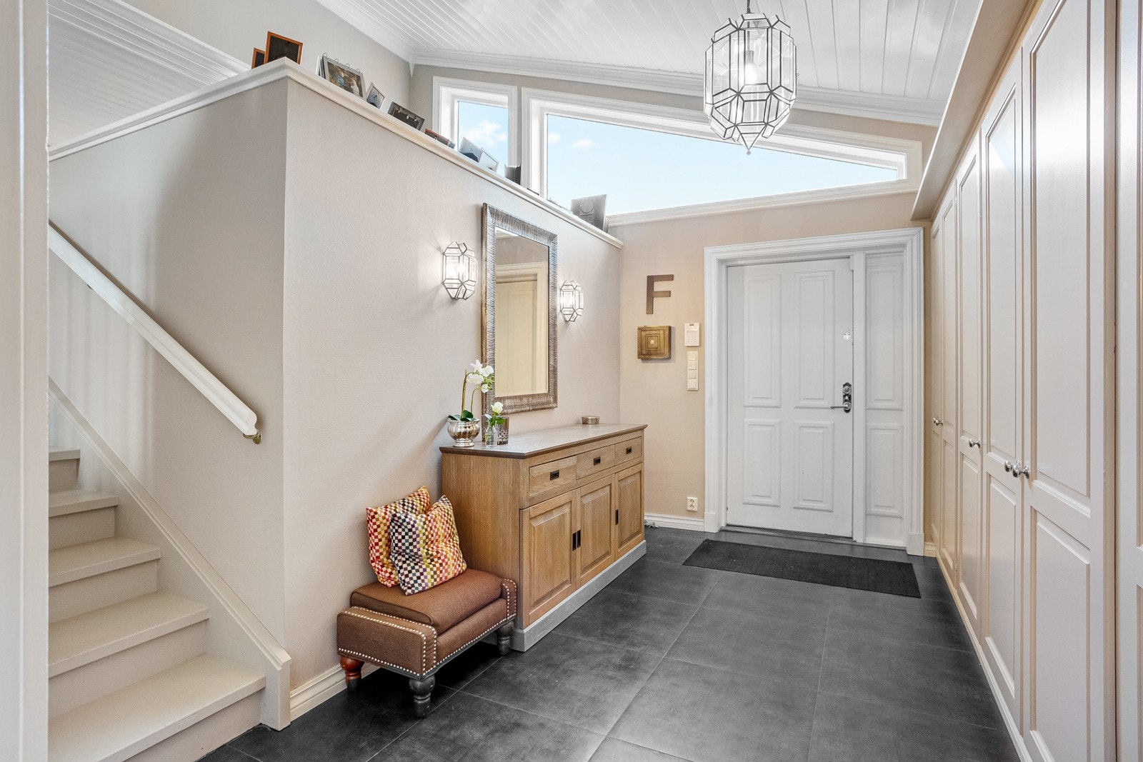 Stor og innbydende flislagt entré, med plassbygd garderobeinnredning. Galleribilde