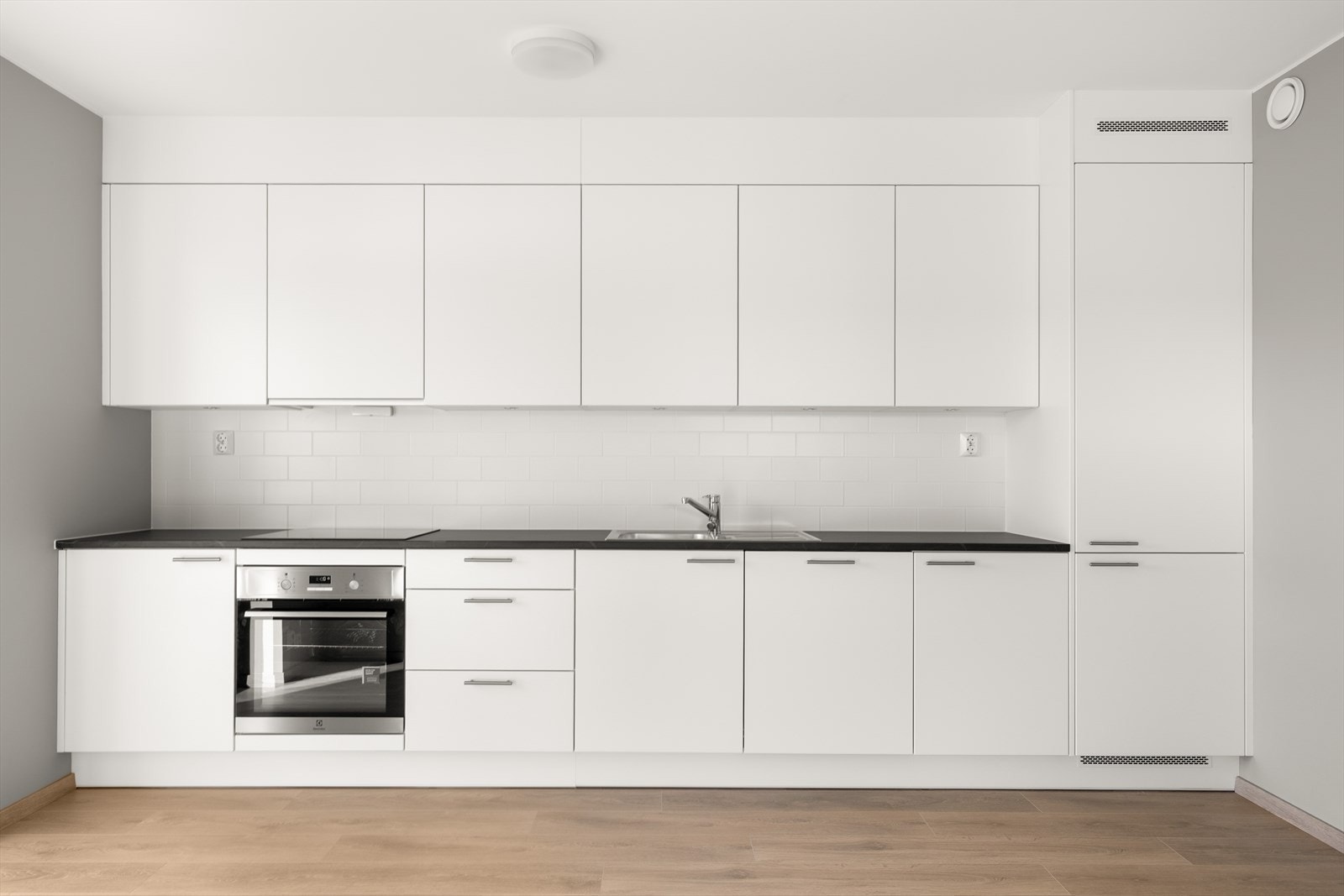 Mellom benkeplate og overskap er det fliser, og overskapene har integrert belysning. Galleribilde