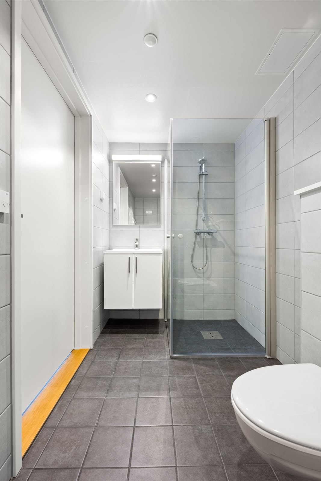 Vegghengt wc, dusjhjørne, opplegg til vask og tørk, samt servant i innredningen. Galleribilde