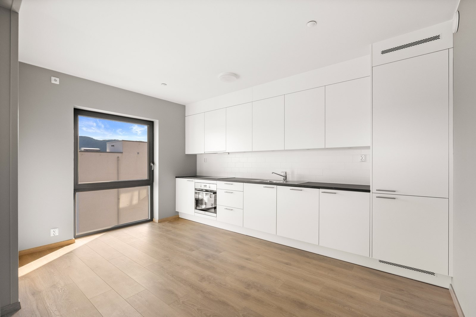 Kjøkkeninnredning med lyse, glatte fronter og en mørkere, slitesterk benkeplate i laminat. Galleribilde